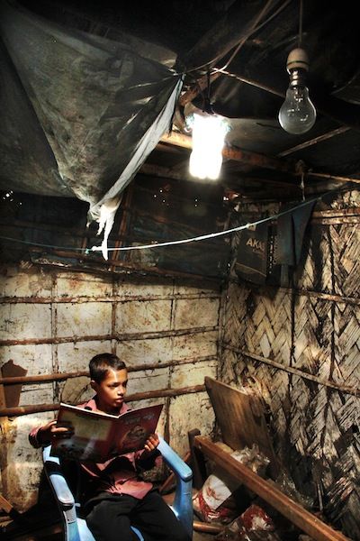 Un bambino impegnato a leggere sotto la luce della lampada solare