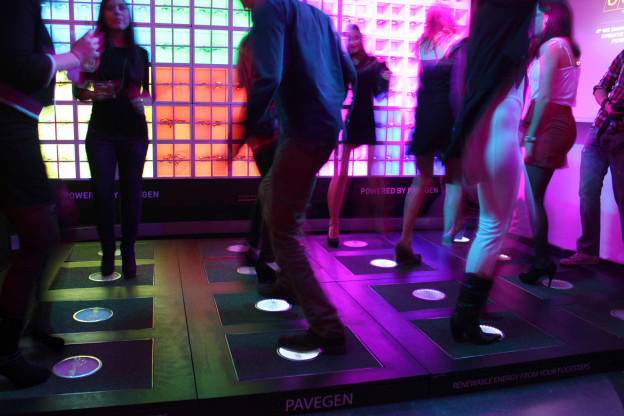 L'immagine raffigura le mattonelle Pavegen in funzione all'interno di una discoteca, dove illumina delle luci installate nel pavimento e su di una parete