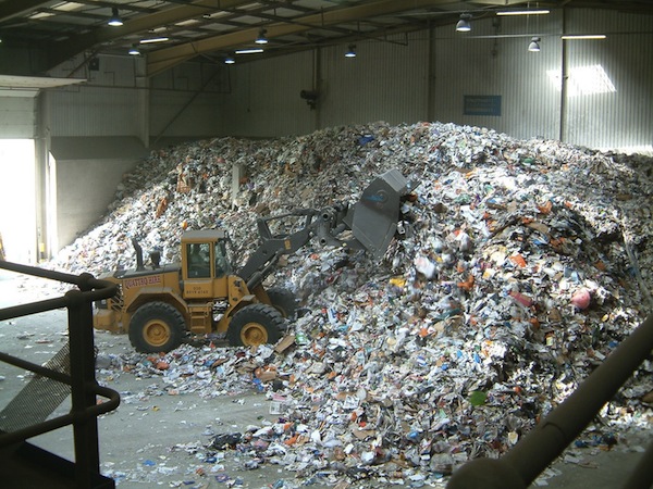 L'immagine ritrae un sito di stoccaggio della plastica ed una ruspa al lavoro per spostarla.