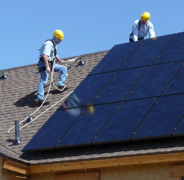 Uomini addetti all'installazione di un impianto fotovoltaico su un tetto di una casa