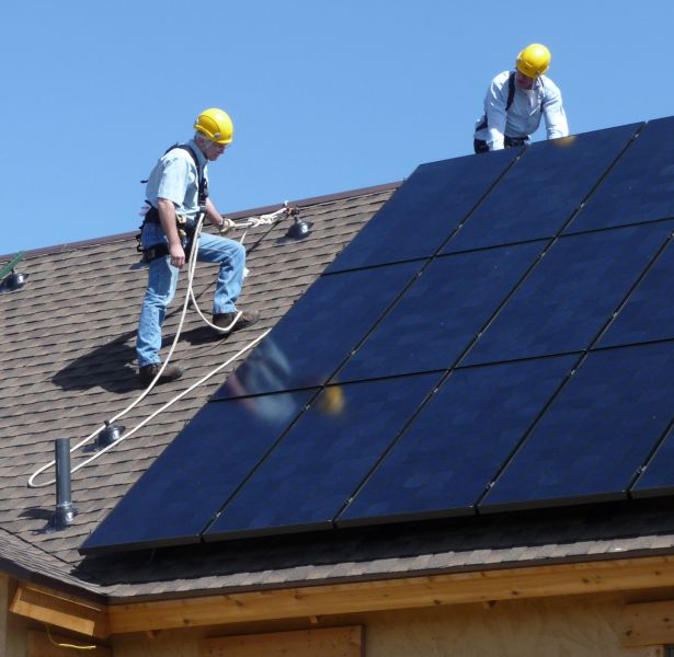 Uomini addetti all'installazione di un impianto fotovoltaico su un tetto di una casa
